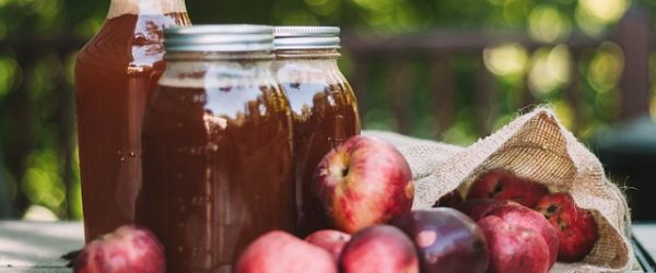 Rote Äpfel und deren Saft in Schraubgläsern 
